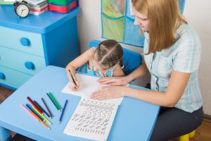 Mentor And Five Year Old Child Learning Spelling